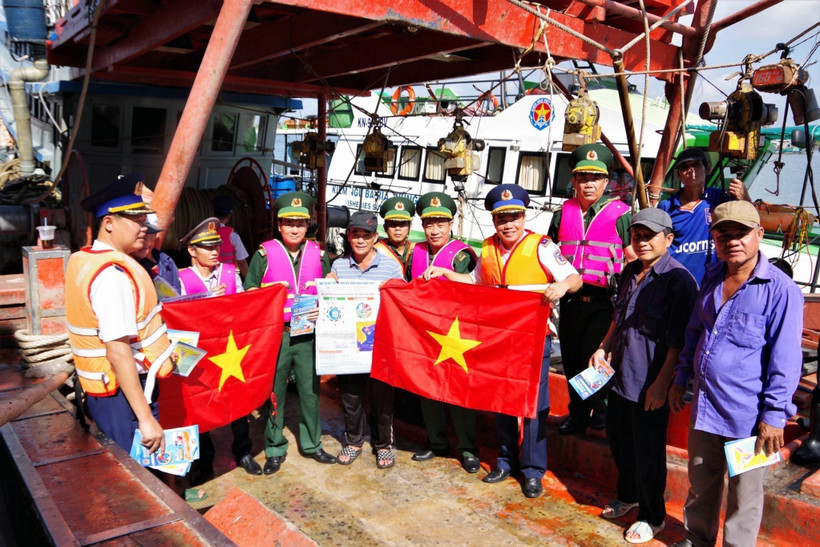 Lực lượng phối hợp tuyên truyền, trao cờ cho ngư dân. Ảnh: TTXVN phát