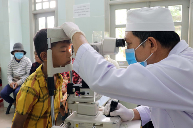 Bác sĩ Bệnh viện Mắt tỉnh Ninh Thuận khám cho trẻ bị đau mắt đỏ. Ảnh: Công Thử - TTXVN Ninh Thuận giám sát, phát hiện sớm, xử lý kịp thời bệnh đau mắt đỏ ảnh 1