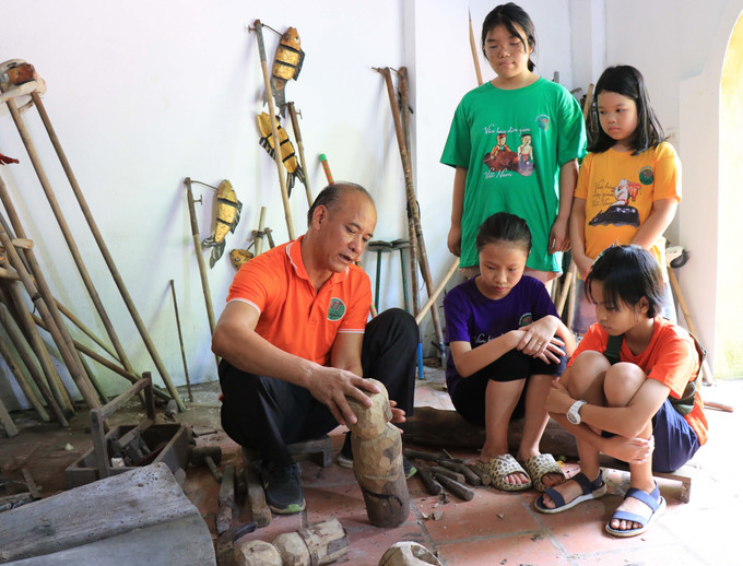 Nghệ nhân Nguyễn Thành Lai, trưởng phường rối nước Luy Lâu giới thiệu con rối đến với các em học sinh. Ảnh: Thanh Thương – TTXVN Bắc Ninh: Gìn giữ nghệ thuật múa rối nước truyền thống ảnh 1