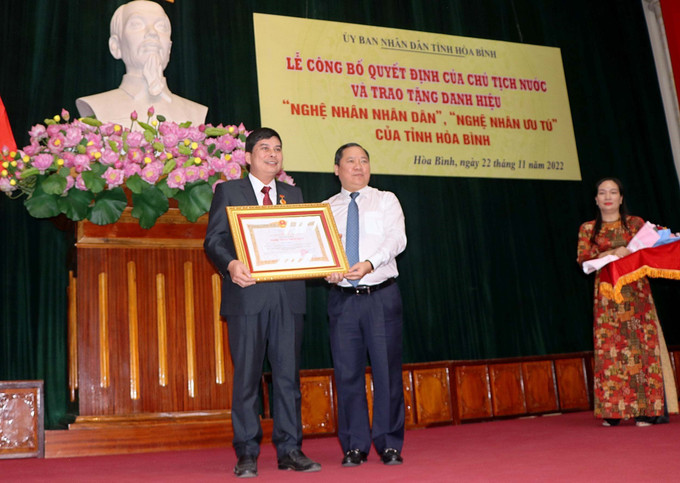 Ông Nguyễn Phi Long, Bí thư Tỉnh ủy Hòa Bình trao Quyết định của Chủ tịch nước phong tặng danh hiệu "Nghệ nhân nhân dân” cho nghệ nhân Bùi Văn Minh. Ảnh: Thanh Hải – TTXVN Công bố Quyết định của Chủ tịch nước và trao tặng danh hiệu “Nghệ nhân nhân dân”, “Nghệ nhân ưu tú” tỉnh Hòa Bình ảnh 2