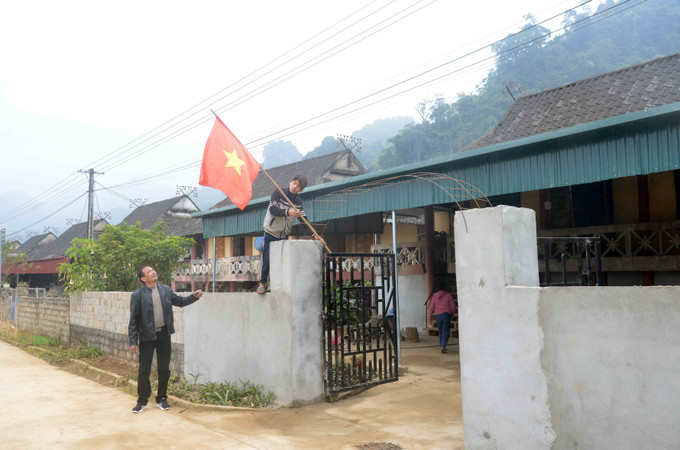 Người dân khu tái định cư bản Dọi, xã Tân Lập treo Cờ tổ quốc chuẩn bị đón Tết. Ảnh: Quang Quyết - TTXVN Đồng bào tái định cư Tân Lập hồ hởi đón Tết ảnh 4