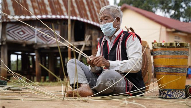 Nghệ nhân làng Mít Jep, xã Ia O (Ia Grai, Gia Lai) chẻ tre đan áo cho cồng, chiêng. Ảnh: Hồng Điệp – TTXVN Người Jrai may áo mới cho cồng, chiêng ảnh 2
