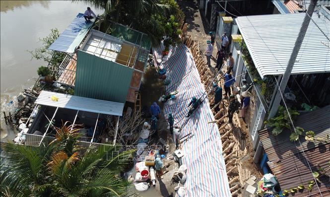 Lực lượng chức năng hỗ trợ người dân di dời tài sản. Ảnh: Nhựt An - TTXVN Đồng Tháp khẩn trương khắc phục vụ sạt lở ven kênh Đốc Phủ Hiền ảnh 1