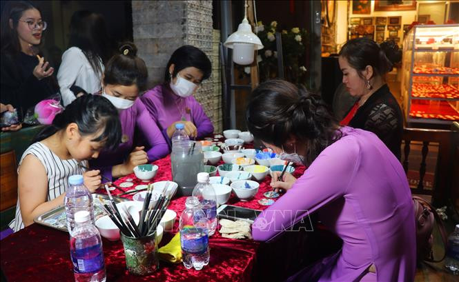 Du khách trải nghiệm làm pháp lam. Ảnh: Tường Vi - TTXVN Khai trương Phố đêm Hoàng thành Huế ảnh 5