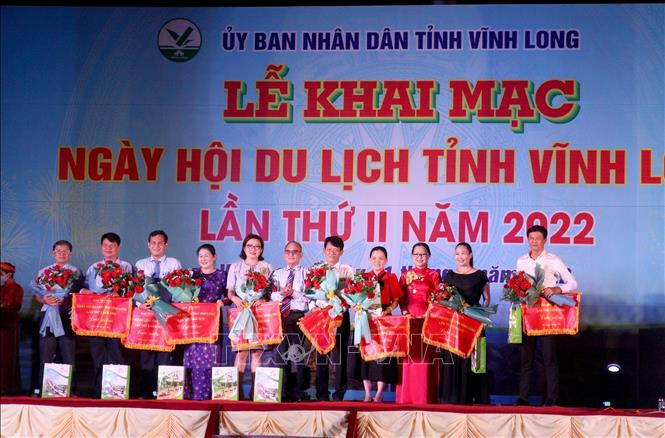 Ban tổ chức tặng hoa và cờ lưu niệm cho các đơn vị tham gia Ngày hội Du lịch tỉnh Vĩnh Long lần II năm 2022. Ảnh: Lê Thúy Hằng – TTXVN Tăng cường liên kết đưa cụm du lịch phía Đông đồng bằng sông Cửu Long phục hồi và phát triển ảnh 5
