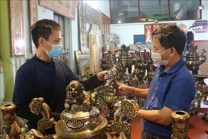 Nghệ nhân Nguyễn Văn Đông giới thiệu sản phẩm của làng nghề cho khách hàng. Ảnh: Thanh Thương – TTXVN Phát triển thương hiệu đồng Đại Bái ảnh 1