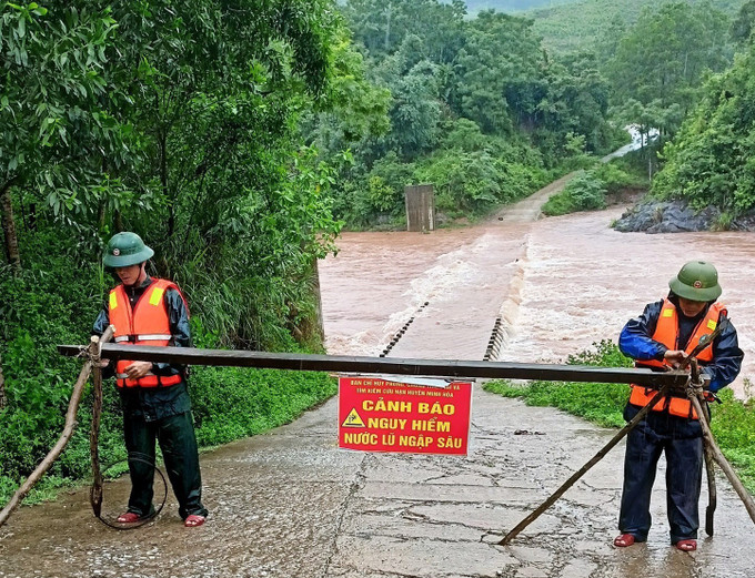 Lực lượng Bộ đội Biên phòng cắm biển báo nguy hiểm, chốt chặn, tuyên truyền, hướng dẫn, nhắc nhở người dân và phương tiện không đi qua vùng nguy hiểm. Ảnh: TTXVN phát Nước lũ dâng gây ngập, chia cắt cục bộ thôn, bản khu vực biên giới tỉnh Quảng Bình ảnh 1