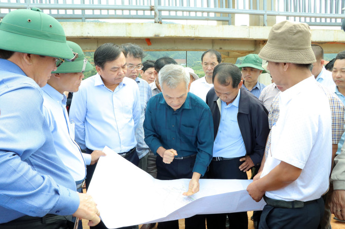 Thứ trưởng Nguyễn Hoàng Hiệp (áo trắng đứng giữa) cùng các chuyên gia phân tích nguyên nhân sạt lở. Ảnh: Nguyễn Dũng-TTXVN Sự cố sạt trượt công trình hồ Đông Thanh: Giải quyết nhu cầu cấp bách cho dân ảnh 1
