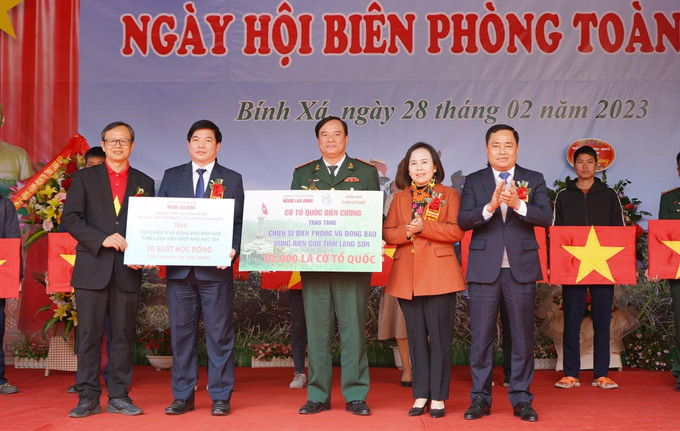 Lãnh đạo tỉnh Lạng Sơn và đại diện báo Người lao động tặng cờ Tổ quốc cho cán bộ, chiến sỹ, nhân dân và trao 30 suất học bổng cho con chiến sĩ và đồng bào biên giới vượt khó học tập. Ảnh: Anh Tuấn – TTXVN Ngày Biên phòng toàn dân: Gắn kết tình quân dân khu vực biên giới ảnh 2