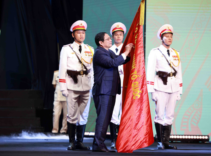 Thủ tướng Phạm Minh Chính gắn Huân chương Hồ Chí Minh lên lá cờ truyền thống của lực lượng Cảnh sát nhân dân, Bộ Công an. Ảnh: Phạm Kiên - TTXVN Lực lượng Cảnh sát nhân dân Việt Nam: Viết tiếp những bản anh hùng ca chiến thắng của thời kỳ mới ảnh 5