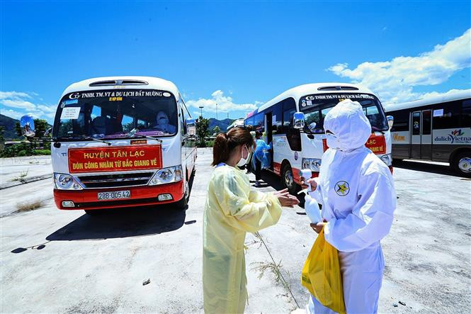 Từng lao động bắt buộc phải thực hiện sát khuẩn trước khi lên xe về địa phương. Ảnh: Trọng Đạt - TTXVN Hòa Bình đón 778 lao động từ Bắc Giang trở về địa phương ảnh 3