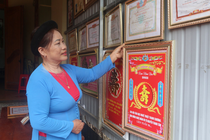 Nghệ nhân ưu tú Nguyễn Thị Tâm bên những giải thưởng mà bà đã đạt được trong hơn 40 năm gắn bó với dân ca ví, giặm. Ảnh: Bích Huệ - TTXVN Nghệ nhân Ưu tú Nguyễn Thị Tâm lan tỏa làn điệu dân ca ví giặm ảnh 1