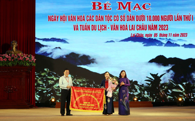 Giám đốc Sở Văn hóa, Thể thao và Du lịch tỉnh Lai Châu Lương Chiến Công trao Cờ đăng cai cho đại diện lãnh đạo Sở Văn hóa, Thể thao và Du lịch tỉnh Lào Cai, đơn vị đăng cai Ngày hội lần thứ hai. Ảnh: Quý Trung – TTXVN Đặc sắc văn hóa các dân tộc ít người ảnh 1