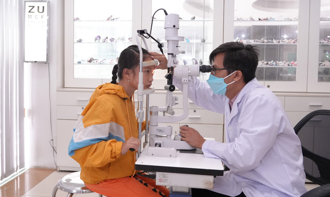 Thạc sĩ, Bác sĩ chuyên khoa mắt Nguyễn Hữu Thế, thăm khám cho bệnh nhi đau mắt đỏ. Ảnh: Minh Phú – TTXVN Long An giám sát, xử lý kịp thời các ổ dịch đau mắt đỏ ảnh 1