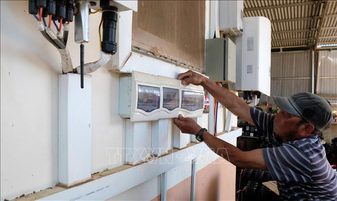 Quản lý trang trại hoa lan Thiên Ngân (huyện Di Linh, tỉnh Lâm Đồng) kiểm tra hệ thống đấu nối công trình điện mặt trời của đơn vị này. Ảnh: Nguyễn Dũng - TTXVN Phát triển điện mặt trời ở Tây Nguyên (Bài 1) ảnh 2