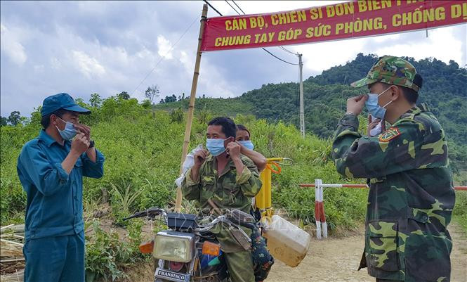 Chiến sĩ Biên phòng hướng dẫn người dân cách đeo khẩu trang đúng cách. Ảnh: Xuân Tư – TTXVN Điện Biên đảm bảo an ninh trật tự và công tác phòng dịch COVID-19 ở vùng biên ảnh 3