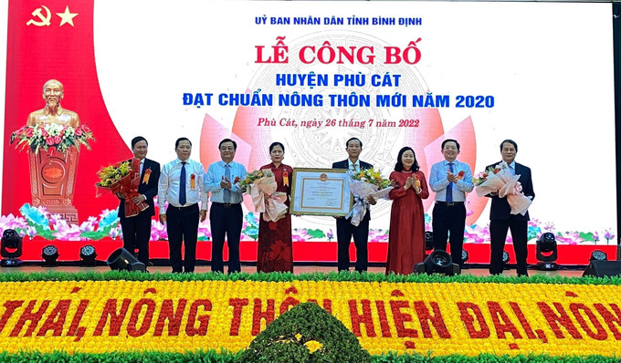 Thừa ủy quyền của Thủ tướng Chính phủ, Đồng chí Bùi Thị Minh Hoài, Bí thư Trung ương Đảng, Trưởng ban Ban Dân vận Trung ương trao Quyết định công nhận huyện Phù Cát đạt chuẩn nông thôn mới cho lãnh đạo huyện. Ảnh: Tường Quân - TTXVN Bình Định tổ chức lễ công bố huyện Phù Cát đạt chuẩn nông thôn mới ảnh 1