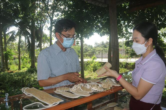 Anh Phạm Văn Đoàn giới thiệu các sản phẩm làm từ xơ mướp với khách hàng. Ảnh: Hoàng Nhị - TTXVN Anh Phạm Văn Đoàn người tạo thương hiệu riêng từ sản phẩm đồ gia dụng bằng xơ mướp ảnh 2