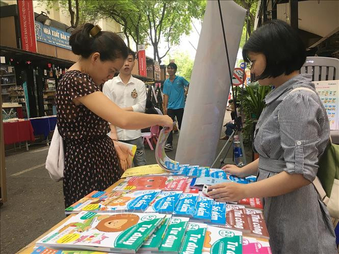Các phụ huynh lựa chọn bộ sách giáo dục dành cho lứa tuổi nhi đồng tại Đường Sách Nguyễn Văn Bình. Ảnh: Thanh Vũ - TTXVN Bộ sách hay hè năm 2020 dành cho lứa tuổi nhi đồng ảnh 4