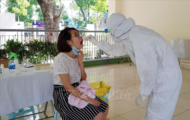 Nhân viên y tế quận Ba Đình thực hiện lấy mẫu xét nghiệm dịch hầu họng cho người dân từ Đà Nẵng trở về. Ảnh: Mạnh Khánh-TTXVN Thêm hai ca mắc COVID-19 tại Hà Nội và Bắc Giang ảnh 1