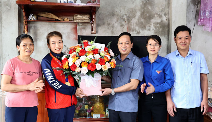 Lãnh đạo UBND huyện Yên Lập tặng hoa và quà chúc mừng vận động viên Triệu Thị Phương Thủy, đạt Huy chương Vàng SEA Games 32. Ảnh: Trung Kiên – TTXVN SEA Games 32: Cô gái dân tộc Dao Triệu Thị Phương Thủy mang Huy chương Vàng về cho Tổ quốc ảnh 5