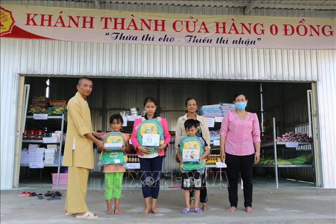 Đại đức Thích Chơn Trí cùng đại diện Ủy ban nhân dân xã Tân Hộ Cơ trao quà cho các em để nhân dịp năm học mới. Ảnh: Chương Đài - TTXVN Dịch COVID-19: Ấm lòng với “Cửa hàng 0 đồng” trên miền biên giới Đồng Tháp ảnh 3
