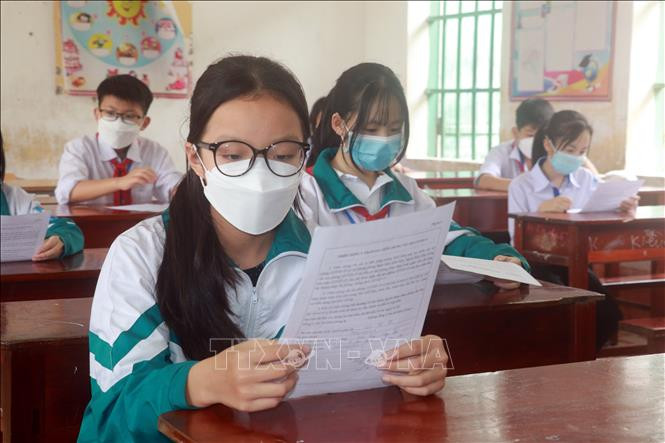 Học sinh lớp 6, Trường Trung học cơ sở đọc những lưu ý về tiêm chủng, chờ đến lượt tiêm vaccine phòng COVID-19 tại trường. Ảnh: Văn Đạt - TTXVN Bộ Y tế đề xuất thí sinh F0 cách ly tại nhà được dự thi tốt nghiệp Trung học Phổ thông năm 2022 ảnh 1