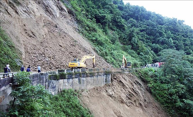 Phương tiện máy móc triển khai san gạt đất, đá sạt lở trên Quốc lộ 8A. Ảnh: TTXVN Hà Tĩnh: Tập trung khắc phục hậu quả mưa, lũ đảm bảo đời sống nhân dân ảnh 1
