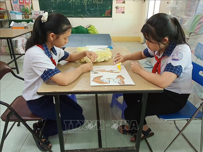 Các em đang thử nghiệm trên dòng vật liệu tái chế mới là vỏ các loại trứng. Ảnh: Ánh Tuyết - TTXVN Độc đáo Dự án “Tranh gạo và hướng phát triển” của hai nữ sinh Cần Thơ ảnh 4