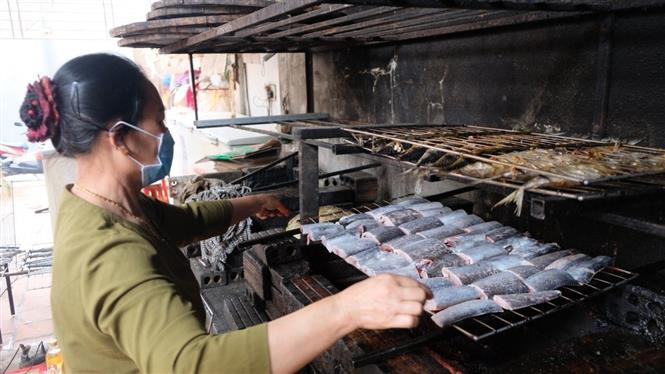 Đưa cá lên giàn nướng than. Ảnh: TTXVN Làng nghề nướng cá nơi cửa biển Ngư Lộc (Thanh Hóa) tất bật vào vụ Tết ảnh 3