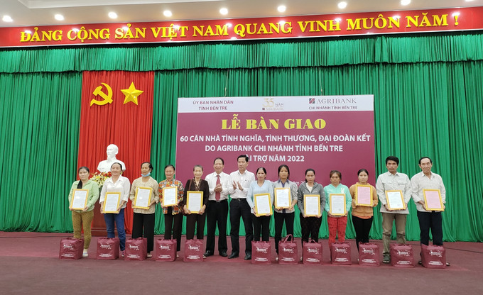 Trao giấy chứng nhận và quà cho hộ dân. Ảnh: Huỳnh Phúc Hậu - TTXVN Bến Tre: Bàn giao 60 căn nhà tình nghĩa, tình thương, đại đoàn kết ảnh 1