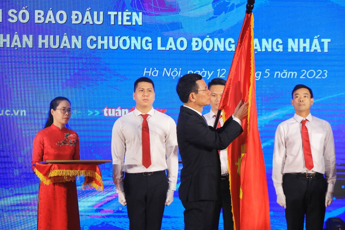 Bộ trưởng Bộ Thông tin và Truyền thông Nguyễn Mạnh Hùng gắn Huân chương Lao động hạng Nhất lên lá cờ truyền thống của Báo Tin tức. Ảnh: Tuấn Anh - TTXVN Báo Tin tức kỷ niệm 40 năm Ngày xuất bản số đầu tiên ảnh 1