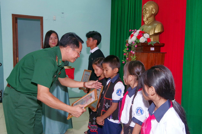 Đại tá Đặng Ngọc Hiệu, Phó Chính ủy Bộ đội Biên phòng tỉnh Thừa Thiên - Huế tặng giấy khen cho học sinh có thành tích xuất sắc trong học tập thuộc chương trình " Nâng bước em tới trường’’. Ảnh: TTXVN phát Thừa Thiên - Huế: Chắp cánh ước mơ cho trẻ em nghèo vùng biên giới ảnh 3