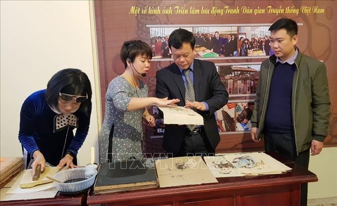 Đại biểu được hướng dẫn làm thử tranh dân gian. Ảnh: Minh Thu- TTXVN Trưng bày tranh dân gian truyền thống Việt Nam ảnh 3