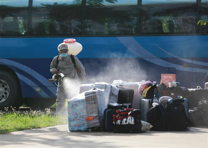 Lực lượng chức năng phun khử khuẩn toàn bộ hành lý của các công dân trước khi đưa vào khu cách ly. Ảnh: Trọng Đạt - TTXVN Hòa Bình tiếp nhận 91 công dân từ Đài Loan (Trung Quốc) về cách ly tại Trung đoàn 814 ảnh 4