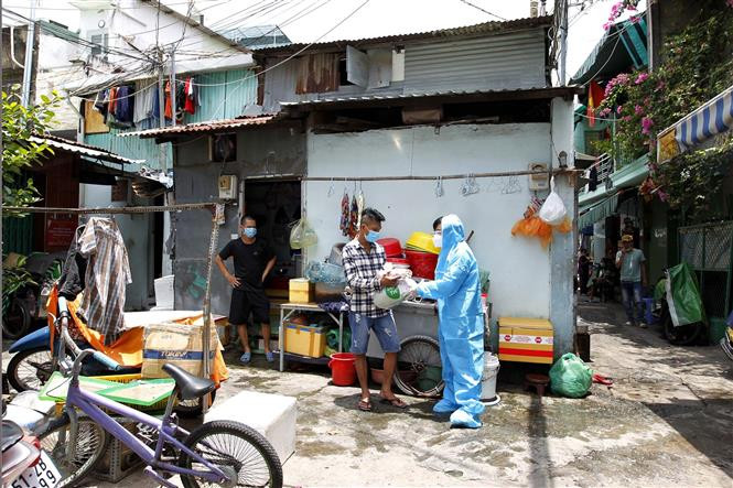 Tình nguyện viên chương trình "Siêu thị 0 đồng di động" của NovaGroup trao quà cho người lao động nghèo trong những con hẻm nhỏ, đông dân cư tại Quận 8. Ảnh: Thanh Vũ - TTXVN Phát huy sức mạnh đại đoàn kết trong xây dựng và phát triển đất nước (Bài cuối) ảnh 3