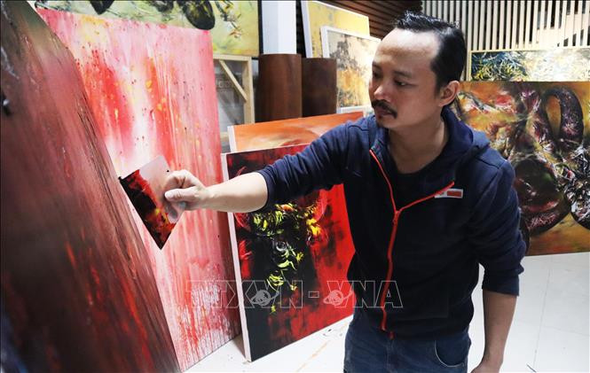 Họa sĩ Ngô Thanh Hùng sáng tác tranh tại nhà. Ảnh: Văn Dũng - TTXVN Họa sĩ Ngô Thanh Hùng - Người thổi hồn vào tranh vẽ trâu ảnh 3
