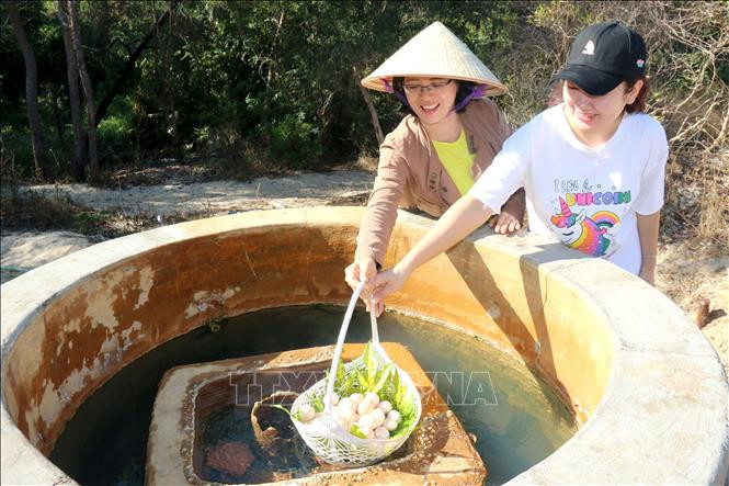 Du khách thích thú tự tay luộc trứng tại giếng nước nóng tự nhiên đổ ra Suối nước nóng Bưng Thị, huyện Hàm Thuận Nam (tỉnh Bình Thuận). Ảnh: Nguyễn Thanh - TTXVN Khai thác tiềm năng phát triển du lịch Hàm Thuận Nam ảnh 1