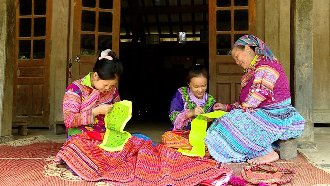 Bà Cù Thị Triệu, thôn Khuổi Khít, xã Kiến Thiết (huyện Yên Sơn, tỉnh Tuyên Quang) dạy các cháu gái kỹ thuật thêu hoa văn trên trang phục truyền thống. Ảnh: Vũ Quang - TTXVN Gìn giữ nghệ thuật thêu hoa văn trên trang phục truyền thống người Mông Hoa ảnh 1
