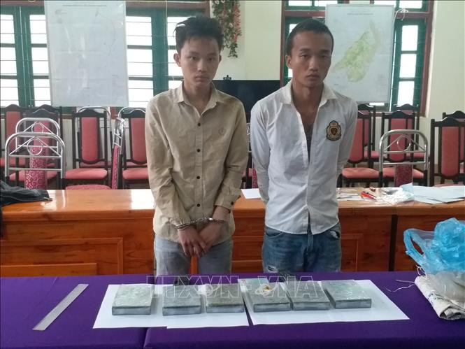 Hai đối tượng bị bắt cùng toàn bộ tang vật. Ảnh: TTXVN Lào Cai: Bắt đối tượng vận chuyển 6 bánh heroin đã có lệnh truy nã ảnh 1