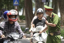 Lực lượng chức năng nhắc nhở, xử lý các trường hợp không đeo khẩu trang nơi công cộng. Ảnh: Minh Quyết - TTXVN
