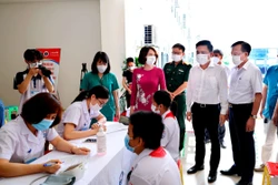 Thứ trưởng Bộ Y tế Nguyễn Thị Liên Hương, Phó Chủ tịch UBND tỉnh Vĩnh Phúc Vũ Việt Văn kiểm tra công tác tư vấn, khám sàng lọc cho các em học sinh trước khi tiêm vaccine phòng COVID-19. Ảnh: Nguyễn Thảo – TTXVN 