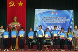 Đại diện Quỹ học bổng Vừa A Dính trao học bổng và đồ dùng học tập cho các em học sinh có hoàn cảnh khó khăn. Ảnh: Khoa Chương – TTXVN