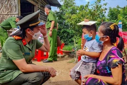 Nữ cán bộ Công an TP Cần Thơ trò chuyện với bé Nguyễn Huỳnh Gia Bảo (xã Tân Thới, huyện Phong Điền) có cha mất do COVID-19. Ảnh: Thanh Liêm - TTXVN