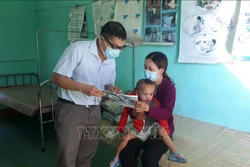 Cán bộ y tế địa phương phát tờ rơi tuyên truyền về bệnh bạch hầu để người dân phòng tránh. Ảnh: Hồ Cầu-TTXVN