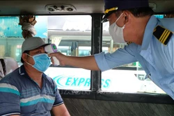 Lực lượng chức năng bến xe phía Bắc thành phố Nha Trang kiểm tra thân nhiệt hành khách khi lên xe. Ảnh: Nguyễn Dũng – TTXVN