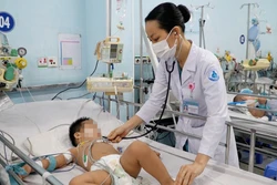 Bác sĩ Bệnh viện Nhi đồng 1 Thành phố Hồ Chí Minh thăm khám cho trẻ mắc bệnh tay chân miệng. Ảnh: TTXVN phát