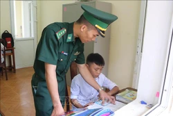 Chiến sĩ Đồn Biên phòng trực tiếp tiếp kèm cặp, hỗ trợ các cháu con nuôi của đơn vị học tập hằng ngày. Ảnh: Xuân Tiến – TTXVN 
