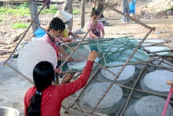 Gỡ bánh sau khi bánh tráng đã được phơi khô. Ảnh: Nguyễn Thanh - TTXVN 