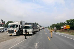 Cảnh sát giao thông hướng dẫn xe vào chốt liên ngành kiểm soát phòng, chống dịch COVID-19 trên quốc lộ 1A thuộc huyện Hàm Tân, Bình Thuận. Ảnh: Nguyễn Thanh - TTXVN 